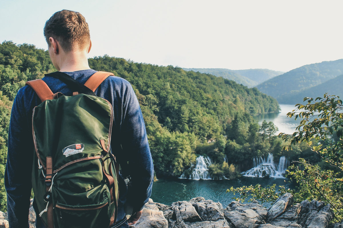 Adventurer with backpack looks at waterfalls in plitvice lakes