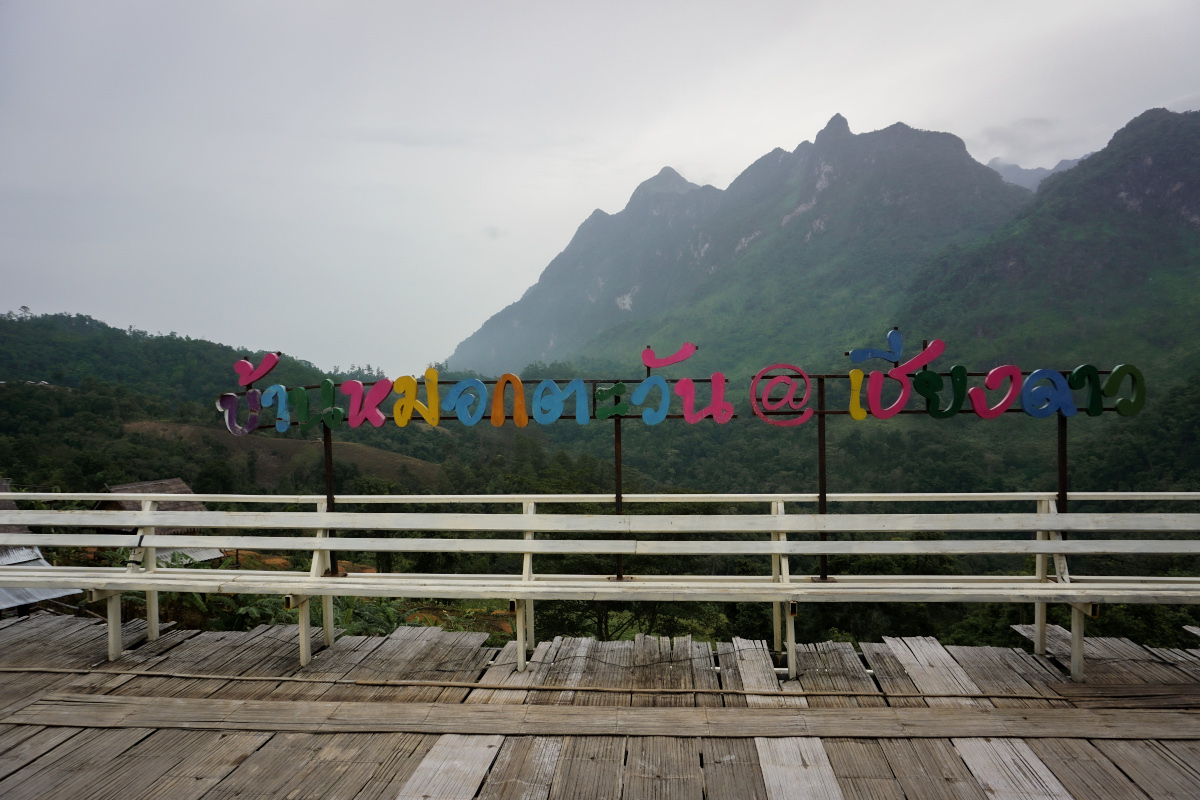 Thai letters on a fence with mountains in the background