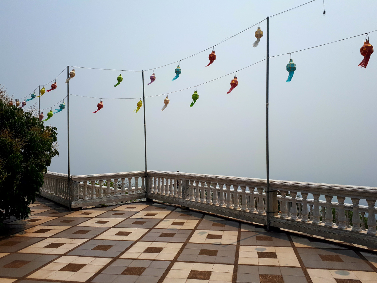 Aussichtsplattform mit bunten Laternen und Nebel, der die Aussicht versperrt