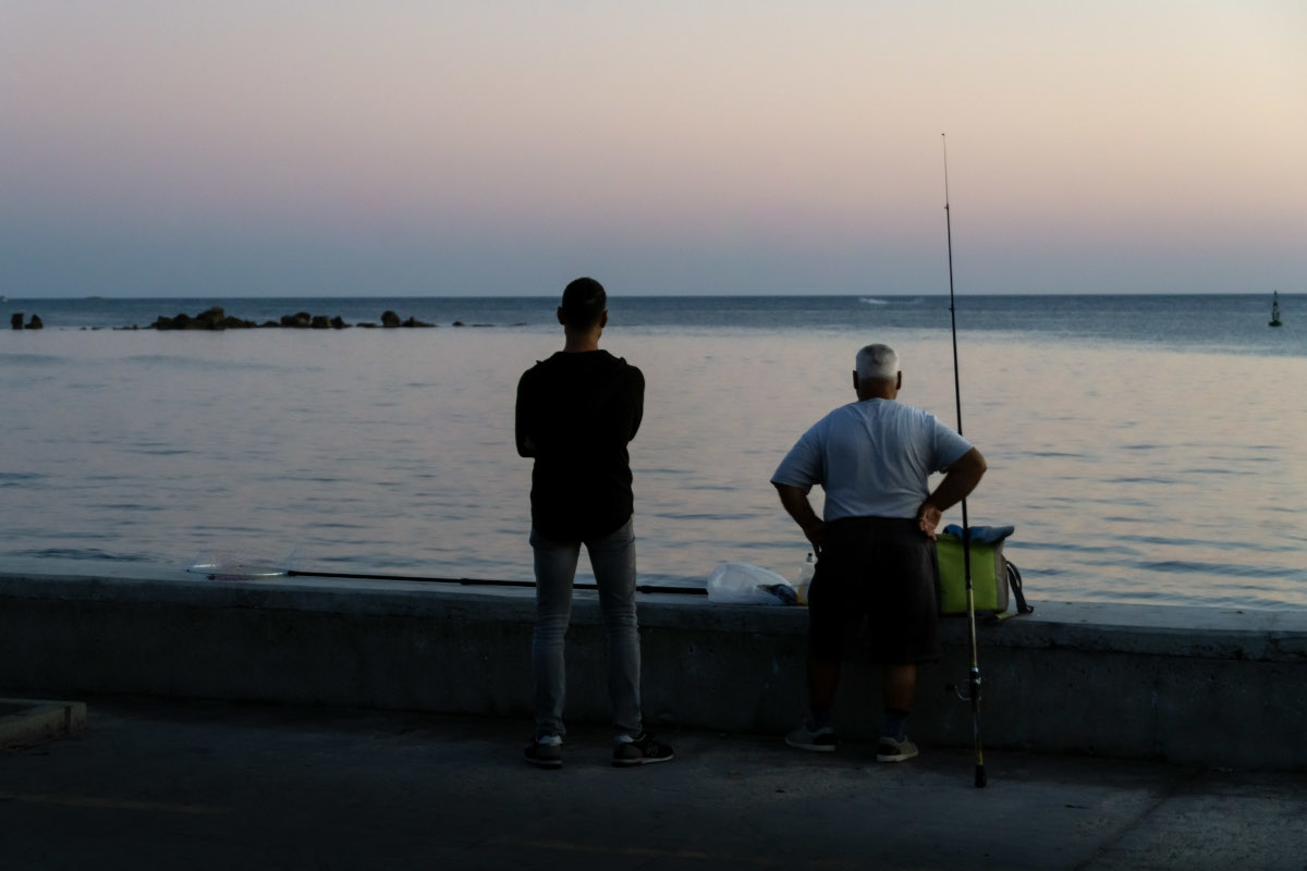 Two fishermen on the coast of Cyprus at sunset