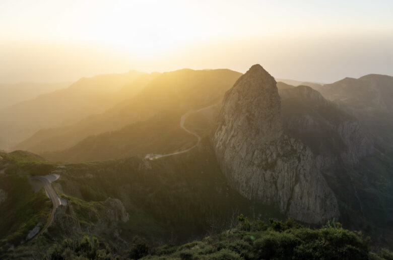 Aussicht auf den Roque de Agando auf La Gomera bei Sonnenaufgang, umgeben von Bergen und kurvigen Straßen