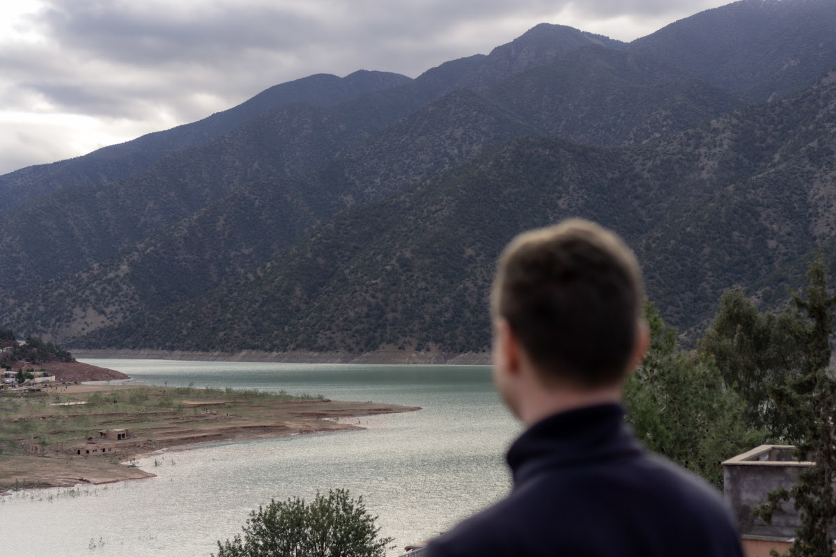 Mann blickt auf See und Berge im Atlasgebirge, Marokko